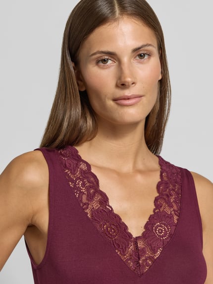 Vrouwenmodel draagt Regular Fit top uit viscosemix model 'ROSA' van VERO MODA in donkerroze, kanten V-hals, dames top, Nahaufnahme bovenlichaam.