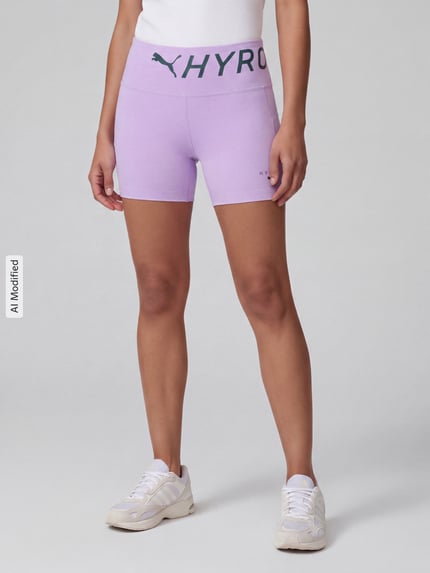 Frauenmodel trägt Skinny Fit Sportshorts mit Label-Print Modell 'PUMA x HYROX PWRMODE 4' von PUMA in Flieder, Ganzkörperansicht von vorne, Damen Sportshorts von PUMA Performance, KI-modifiziertes Bild.