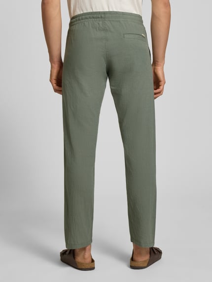 Männermodel trägt grüne Hose aus Baumwoll-Leinen-Mix Modell 'KANE' von Jack & Jones, Regular-Fit, elastischer Bund, Ganzkörperansicht Rückansicht.