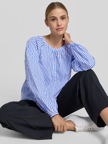 Kobiece model prezentuje Regular Fit Bluse mit Rundhalsausschnitt von Christian Berg Woman z bawełny, wzór na całej powierzchni, listwa guzikowa, okrągły dekolt, długość tyłu w rozmiarze 36: 55 cm, długość rękawów w rozmiarze 36: 63 cm, zdjęcie całej sylwetki z przodu.