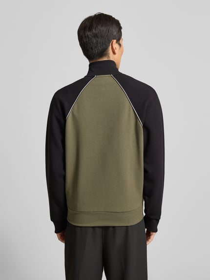 Männermodel trägt Regular Fit Sweatjacke aus Baumwoll-Mix von BOSS Green in Oliv und Schwarz mit Kontraststreifen, Ganzkörperansicht Rückansicht.