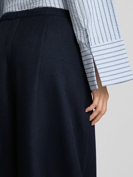 Frauenmodel trägt Culotte mit elastischem Bund und Kordelzug Modell 'Eveline' von Neo Noir, dunkelblau, feine Struktur, Nahaufnahme Oberkörper, Kontext: Damen Culotte Loose Fit, Bundweite 37 cm, Innenbeinlänge 72 cm.