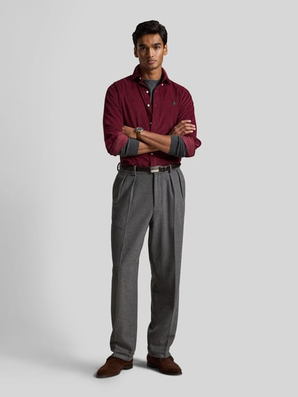 Männermodel trägt Custom Fit Freizeithemd aus reiner Baumwolle von Polo Ralph Lauren in Dunkelrot vor hellgrauem Hintergrund, Ganzkörperansicht von vorne.