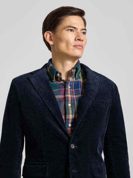 Männermodel trägt Sakko mit Cordstruktur von POLO RALPH LAUREN in Dunkelblau, einfarbig, Reverskragen, Brustleistentasche, Nahaufnahme Oberkörper.