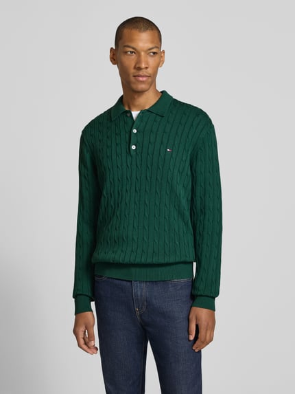 Männermodel trägt Regular Fit Pullover aus reiner Baumwolle von Tommy Hilfiger in Dunkelgrün mit Strickstruktur, Ganzkörperansicht von vorne. Herren Pullover von Tommy Hilfiger.