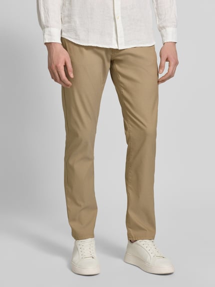 Mężczyzna nosi Fein strukturierte Hose mit Label-Detail od Pierre Cardin, beżowy odcień, bawełniany miks z dodatkiem stretchu, krój regular fit, miękka faktura, szerokość w rozmiarze 32/32: 43 cm, długość nogawki: 79 cm, zdjęcie całej sylwetki z przodu.
