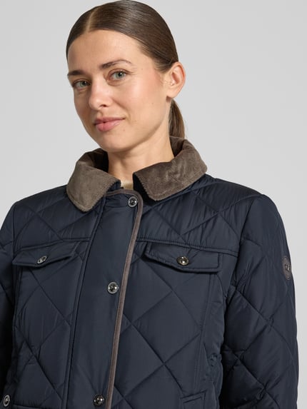 Frauenmodel trägt Relaxed Fit Steppjacke mit abnehmbarer Kapuze von Gil Bret, dunkelblau mit gestepptem Muster, Nahaufnahme Oberkörper. Damen Steppjacke von Gil Bret.