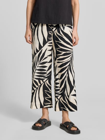 Frauenmodel trägt Wide Fit Stoffhose aus Viskose-Mix Modell 'Life' von Mango mit floraler Allover-Print, verkürzt, elastischer Bund, Nahaufnahme Unterkörper.