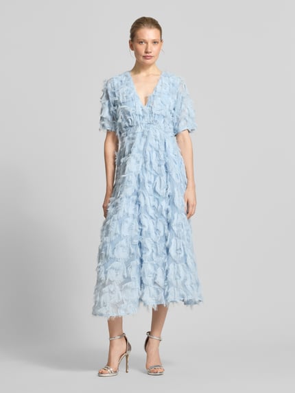Frauenmodel trägt hellblaues Cocktailkleid mit Fransen Modell 'PAZYLLA' von YAS, A-Linie, V-Ausschnitt, Midikleid, Ganzkörperansicht von vorne. Rückenlänge bei Größe 36: 125 cm, Brustweite bei Größe 36: 43 cm, Ärmellänge bei Größe 36: 28 cm.