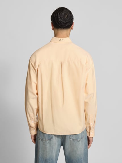 Męski model nosi Regular Fit Freizeithemd mit floralem Stitching od ANOTHER COTTON LAB, mieszanka bawełny, brustasza, kołnierzyk typu button down, listwa guzikowa, detal z logo, gładki materiał, jasny kolor, długość tyłu w rozmiarze M 72 cm, szerokość w rozmiarze M 54 cm, długość rękawów w rozmiarze M 63 cm, widok całej sylwetki od tyłu.