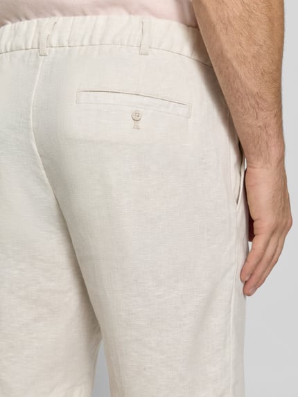 Männermodel trägt Bermudas aus reinem Leinen von JAKE*S STUDIO MEN, lichte beige kleur, losse pasvorm, elastische taille, detailaufnahme rechter heup