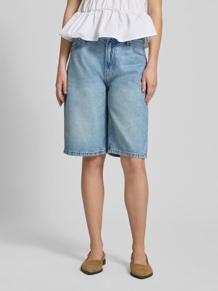 Kobiece model nosi Barrel Shorts im 5-Pocket-Design od Gina Tricot, niebieska bawełna, szerokość w rozmiarze 36: 42 cm, długość wewnętrzna nogawki 28 cm, krój barrel fit, zapięcie na guzik i zamek błyskawiczny, 5 kieszeni, widok całej sylwetki z przodu.