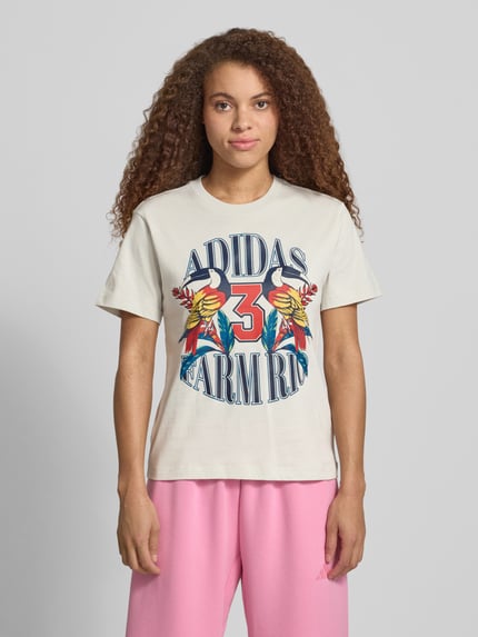 Frauenmodel trägt T-Shirt mit Label-Print von adidas Sportswear aus Reine Baumwolle im Regular-Fit, bunter Print, Ganzkörperansicht von vorne.