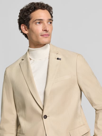 Męski model nosi Regular Fit Sakko aus elastischem Material-Mix mit Label-Detail von bugatti, kolor beżowy, Stójka, zamek błyskawiczny, marynarka na 2 guziki, kołnierz z połami, Brustasza, kieszenie z patką, długość tyłu w rozmiarze 50: 74 cm, szerokość w rozmiarze 50: 43 cm, długość rękawów w rozmiarze 50: 66 cm, ujęcie: zbliżenie na górną część ciała.