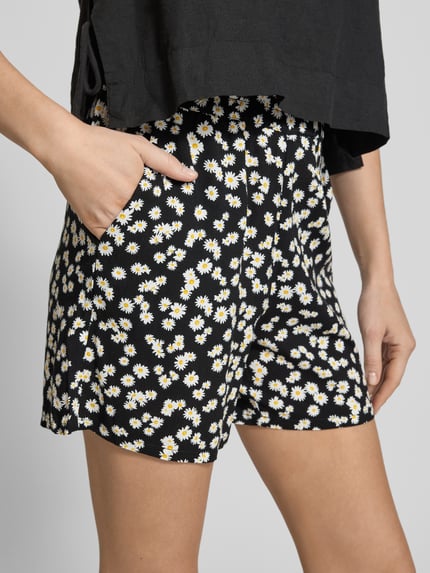 Frauenmodel trägt Loose Fit Shorts aus reiner Viskose Modell 'EASY JOY' von Vero Moda, Optik:Allover-Muster, Eingrifftaschen, Nahaufnahme Oberschenkel.