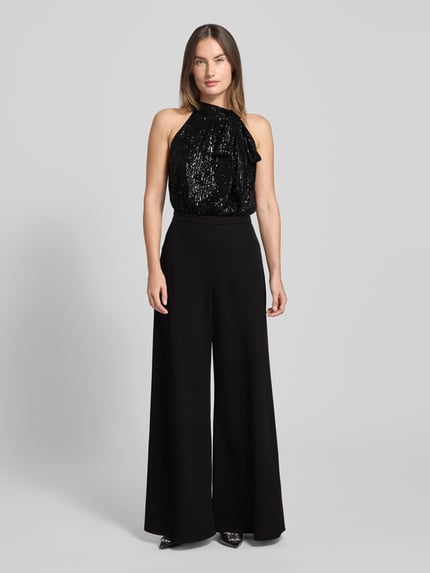 Frauenmodel trägt Regular Fit Jumpsuit mit Pailettenbesatz von Swing, czarny, elastyczny, wiązanie, bez rękawów, z tyłu wycięcie, Ganzkörperansicht von vorne.