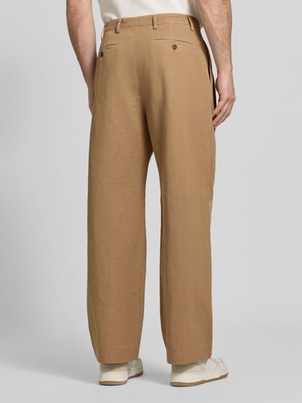 Männermodel trägt Relaxed Fit Stoffhose aus Baumwoll-Leinen-Mix von Paul Smith in Beige mit Kellerfalten, Rückansicht, Ganzkörperansicht. Bundweite 42 cm, Innenbeinlänge 78 cm, Eingriff- und Gesäßtaschen mit Knopf- und Reißverschluss.