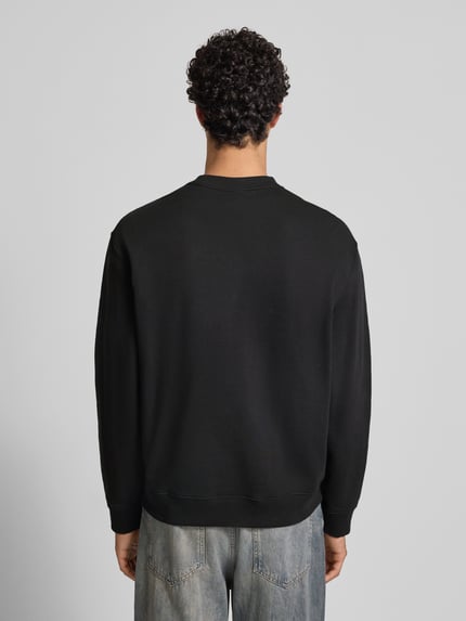 Männermodel draagt Sweatshirt mit Label-Stitching van Calvin Klein Jeans, zwarte katoen, ronde hals, relaxte pasvorm, geribde boorden, Ganzkörperansicht Rückansicht.
