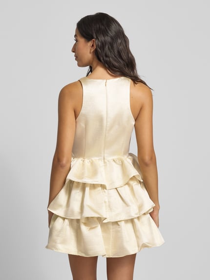 Frauenmodel trägt Cocktailkleid aus Satin im Stufen-Look von Adrianna Papell in Creme, A-Linie, Minilänge, Rückenansicht, Ganzkörperansicht.