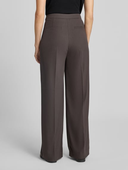 Frauenmodel trägt Relaxed Fit Anzughose mit Viskose-Anteil Modell 'TAILOR' von Cph Muse in Braun, glatte Textur, Ganzkörperansicht Rückansicht.