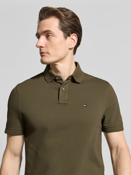 Männermodel trägt Regular Fit Poloshirt aus Baumwoll-Mix von Tommy Hilfiger, Optik: Unifarben, Logo-Stitching, Nahaufnahme Oberkörper.