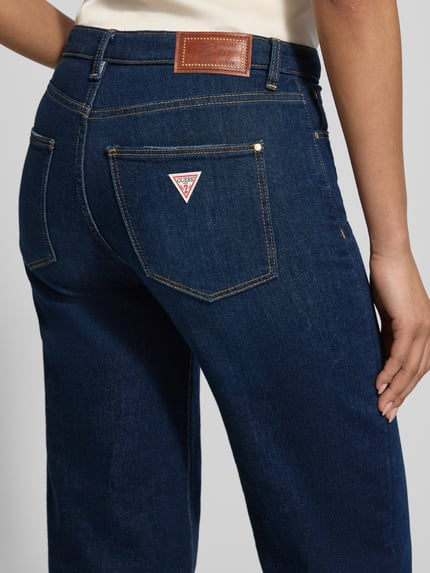 Frauenmodel trägt Wide Leg Jeans mit Eingrifftaschen von Guess in tiefem Blau, robuster Baumwoll-Mix mit Stretch-Anteil, Detailaufnahme Rückansicht. Damen Jeans, High-Waist, sichtbare Bundweite und Gesäßtaschen, Kontext: Bundweite 37 cm, Innenbeinlänge 80 cm, Größe 27/32.