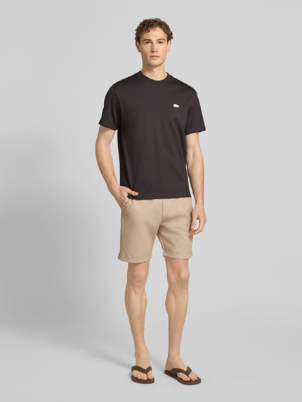 Männermodel trägt Shorts mit elastischem Bund und Gesäßtasche von MCNEAL, beige Farbe, Regular Fit, Ganzkörperansicht von vorne.