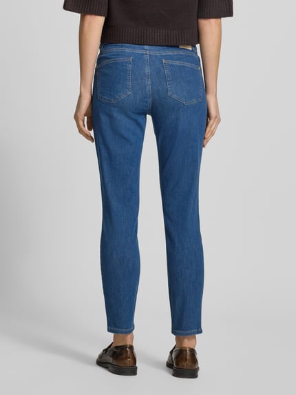 Frauenmodel trägt Slim Fit Jeans mit Eingrifftaschen Modell 'SHAKIRA' von Brax, mittleres Blau, Baumwoll-Mix mit Lyocell, Ganzkörperansicht Rückansicht.