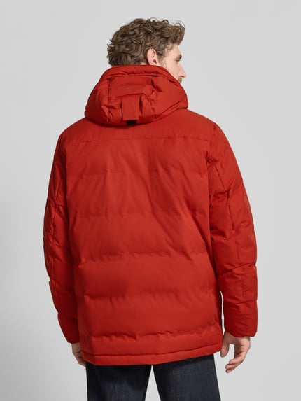 Männermodel trägt Steppjacke mit Pattentaschen von camel active in Rot mit Kapuze, strukturierter Stoff, Rückenlänge 80 cm, Ganzkörperansicht Rückansicht