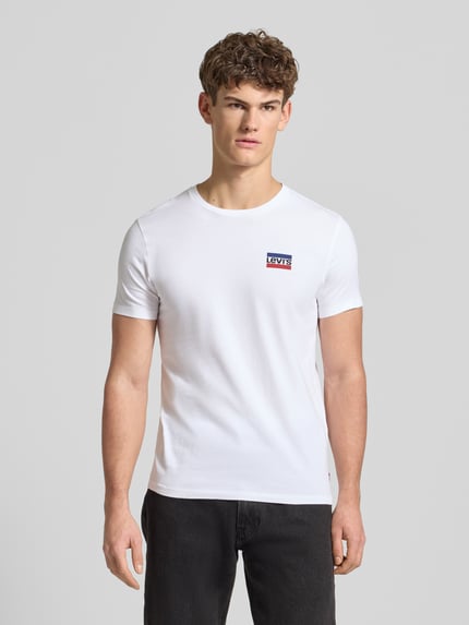 Męski model nosi T-Shirt mit Label-Print im 2er-Pack od LEVI'S®, biała bawełna, krój slim fit, okrągły dekolt, zestaw 2 szt., przód, ujęcie całej sylwetki.