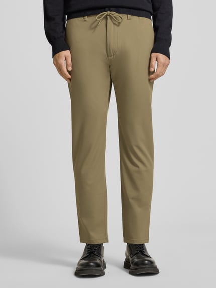 Männermodel trägt Stoffhose mit elastischem Bund von MCNEAL in Beige, Material-Mix mit Viskose-Anteil, Lockerer Schnitt, Ganzkörperansicht von vorne.