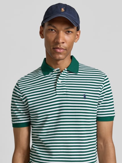Männermodel trägt Slim Fit Poloshirt aus reiner Baumwolle Modell 'YD MESH STRIPE POLO' von Polo Ralph Lauren in grün-weißen Streifen, Nahaufnahme Oberkörper.