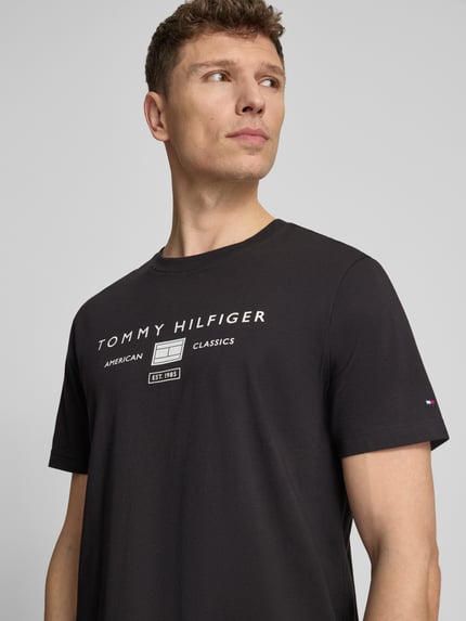 Männermodel trägt Regular Fit T-Shirt aus reiner Baumwolle von Tommy Hilfiger, Optik: Unifarben, Label-Print, Rundhals, Kurzarm, Nahaufnahme Oberkörper.