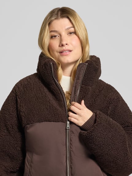 Frauenmodel trägt Steppjacke Modell 'Hazy' mit Fleece-Einsätzen von OPUS in einfarbigem Dunkelbraun, Reißverschluss, elastische Abschlüsse, Webware mit Fleece, seitliche Eingrifftaschen, Nahaufnahme Oberkörper.