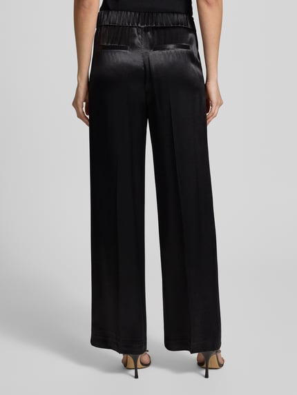 Vrouwenmodel draagt Opus stoffen broek van zuivere viscose, los model, elastische band, steekzakken, model 'Mucia', achteraanzicht.