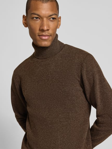 Męski model nosi Slim Fit Rollkragenpullover aus Woll-Mix Modell 'Karl' von Casual Friday, brąz, prążkowane wykończenia, z długim rękawem, prążkowany kołnierz, długość tyłu w rozmiarze M 70 cm, długość rękawów w rozmiarze M 69 cm, mieszanka wełny, widok na górną część tułowia z przodu.