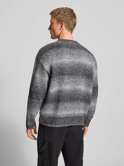 Männermodel trägt Oversized Strickpullover mit gerippten Abschlüssen von Pegador in Grau mit Rundhalsausschnitt, Rückenansicht, Ganzkörperansicht Rückansicht.