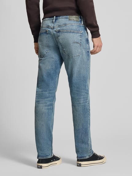 Męski model nosi Slim Tapered Fit Jeans mit Eingrifftaschen Modell 'Streem' od G-Star Raw, bawełna, błękitny denim, krój slim fit, długość nogawki 80 cm, szerokość w rozmiarze 32/32: 44 cm, widok całej sylwetki z tyłu.