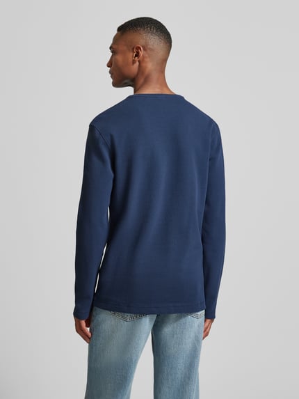 Männermodel trägt Regular Fit Langarmshirt aus Baumwoll-Mix Modell 'TEMPESTO' von BOSS Orange in Blau, Waffel-Optik, Ganzkörperansicht Rückansicht.