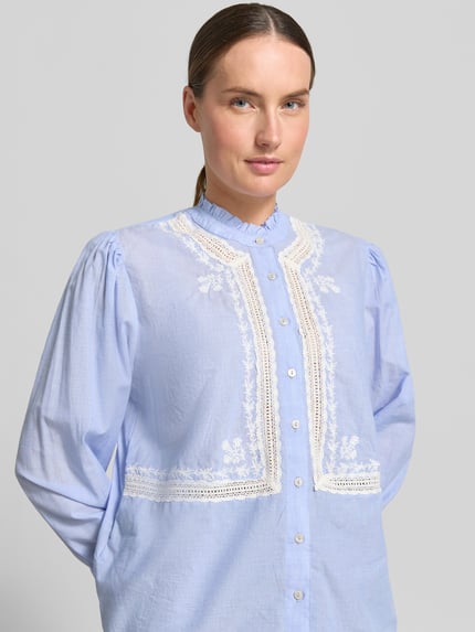 Frauenmodel trägt Bluse mit Rüschenärmeln Modell 'LEONINE' von Mango aus Reine Baumwolle, Straight Fit, Häkelspitze, Knopfleiste, Rüschenkragen, Rückenlänge bei Größe S 61 cm, Ärmellänge 61 cm, Nahaufnahme Oberkörper.