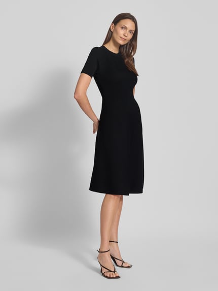 Kobiece modelka nosi czarne, prążkowane knielang Strickkleid in Ripp-Optik mit 1/2-Arm od ARMANI EXCHANGE, dopasowany krój, widok całej sylwetki z przodu.
