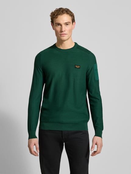 Männermodel trägt Strickpullover mit Label-Detail von PME Legend in Dunkelgrün, reine Baumwolle, Regular Fit, Ganzkörperansicht von vorne.