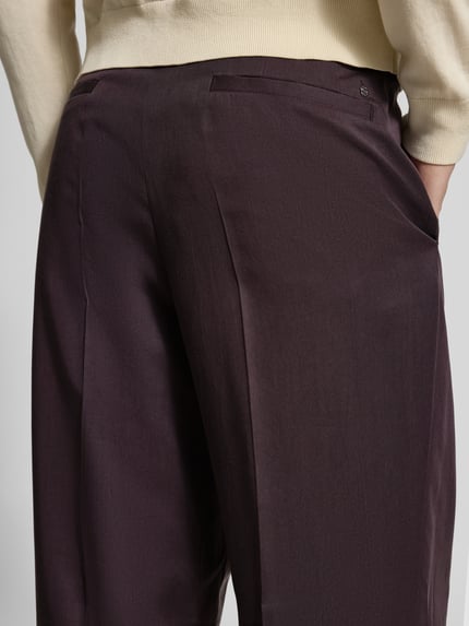 Männermodel trägt spodnie z zakładkami w pasie Wide Leg Bundfaltenhose aus Lyocell Modell 'C-PAT-BB-DPL-262' von BOSS, efekt: jednolity kolor, krój: spodnie z szerokimi nogawkami, detale: zakładki w pasie i kanty, szlufki na pasek, zapięcie: zatrzask i ukryty zamek błyskawiczny, kieszenie: wpuszczane kieszenie boczne i kieszenie z tyłu, materiał: lyocell, zbliżenie na tył spodni