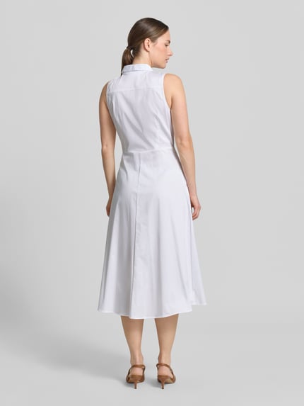 Frauenmodel trägt Hemdblusenkleid aus Satin in Midilänge von Comma im Farbton Weiß mit taillierter Passform aus Baumwoll-Mix, ärmellos, Hemdblusenkragen, durchgängige Knopfleiste und abnehmbarem Taillenband, Rückenlänge bei Größe 36: 120 cm, Brustweite 34 cm, glatte Textur, Ganzkörperansicht Rückansicht.
