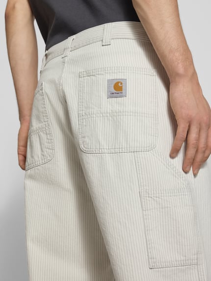 Männermodel trägt Hose aus katoen model 'Mercer' van Carhartt Work In Progress in relaxed fit, lichte kleur, detailopname achterzak, pure katoen, steekzakken, taillewijdte maat M 45 cm, binnenbeenlengte maat M 76 cm. Detailopname rugzijde.