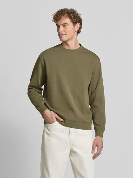 Mannenmodel draagt slim fit pullover uit pure katoen 'TOM' van Selected in olijfgroen met glad oppervlak, heren sweatshirt, frontaal totaalbeeld.