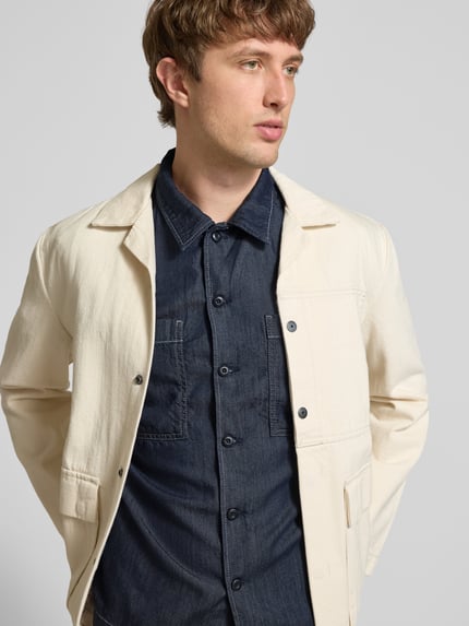 Männermodel trägt Regular Fit Freizeithemd aus Lyocell-Mix Modell 'Bowling' von G-Star Raw in Denim-Optik mit Brust-Taschen, Reverskragen und durchgängiger Knopfleiste, Rückenlänge 72 cm, Schulterbreite 48 cm, Ärmellänge 30 cm, Ganzkörperansicht von vorne.