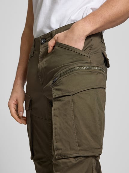 Männermodel trägt Regular Tapered Fit Cargohose mit Reißverschlusstasche von G-Star, Baumwoll-Elasthan-Mix, Nahaufnahme Oberkörper. Herren Cargohose, 5-Pocket-Design, Modell 'Rovic', Bundweite 42 cm, Innenbeinlänge 77 cm.