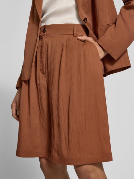Vrouwenmodel draagt Bermudas met Steekzakken van Jake*s Collection in regular fit, roestbruin, knoop- en ritssluiting, binnenbeenlengte 80 cm, paspelzakken achter, bandwijdte 40 cm, detailopname heup tot boven de knie.