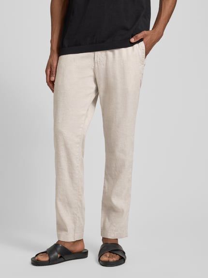 Männermodel trägt Regular Fit Leinenhose aus Leinen-Mix Modell 'SANDERSON' von BOSS Orange in Beige, Flammgarntextur, Nahaufnahme Unterkörperansicht.